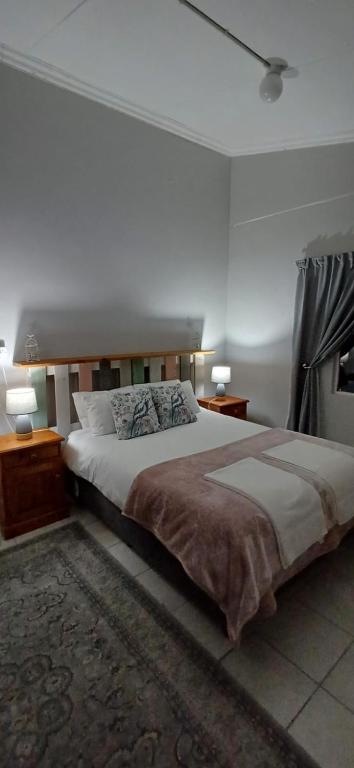 a bedroom with a large bed with two lamps and a rug at Winemaker's Rest- Two Bedroom House in Oudtshoorn