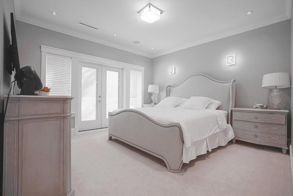 a white bedroom with a large bed and a window at Vancouver Elite Stay close to UBC in Vancouver