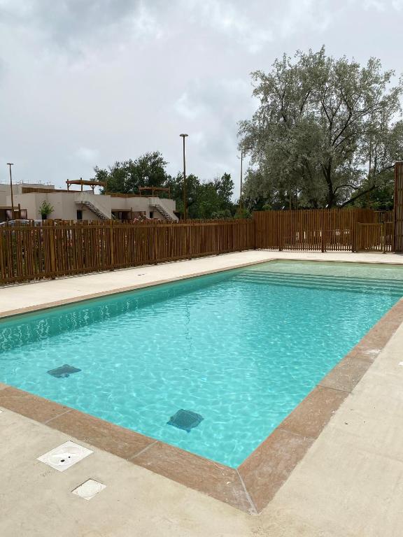 une piscine d'eau bleue en face d'une clôture dans l'établissement T2 tout équipé à 300m de la plage, à Vias