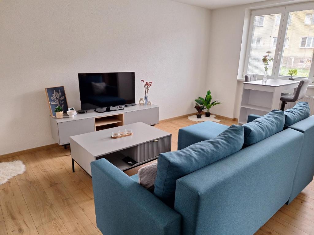 a living room with a blue couch and a tv at Ubytovanie pod Hradovou v Tisovci in Tisovec