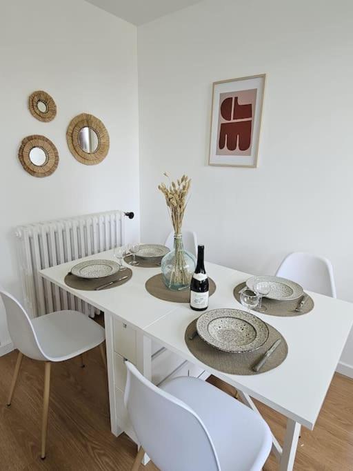 una mesa blanca con sillas y platos y una botella de vino en Superbe appartement rénové, en Bourges