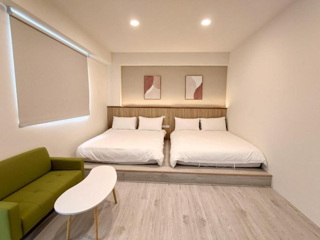 a bedroom with two beds and a green couch at 花蓮後站-沐青文旅 in Hualien City