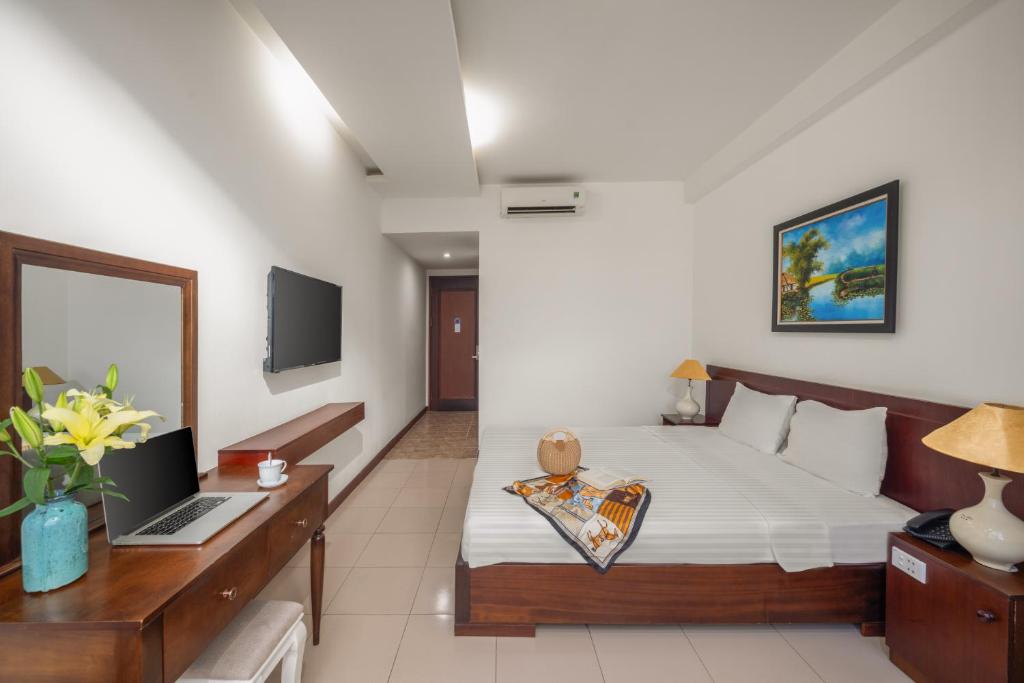 a bedroom with a bed and a laptop on a desk at Star Hotel and Spa Danang in Danang
