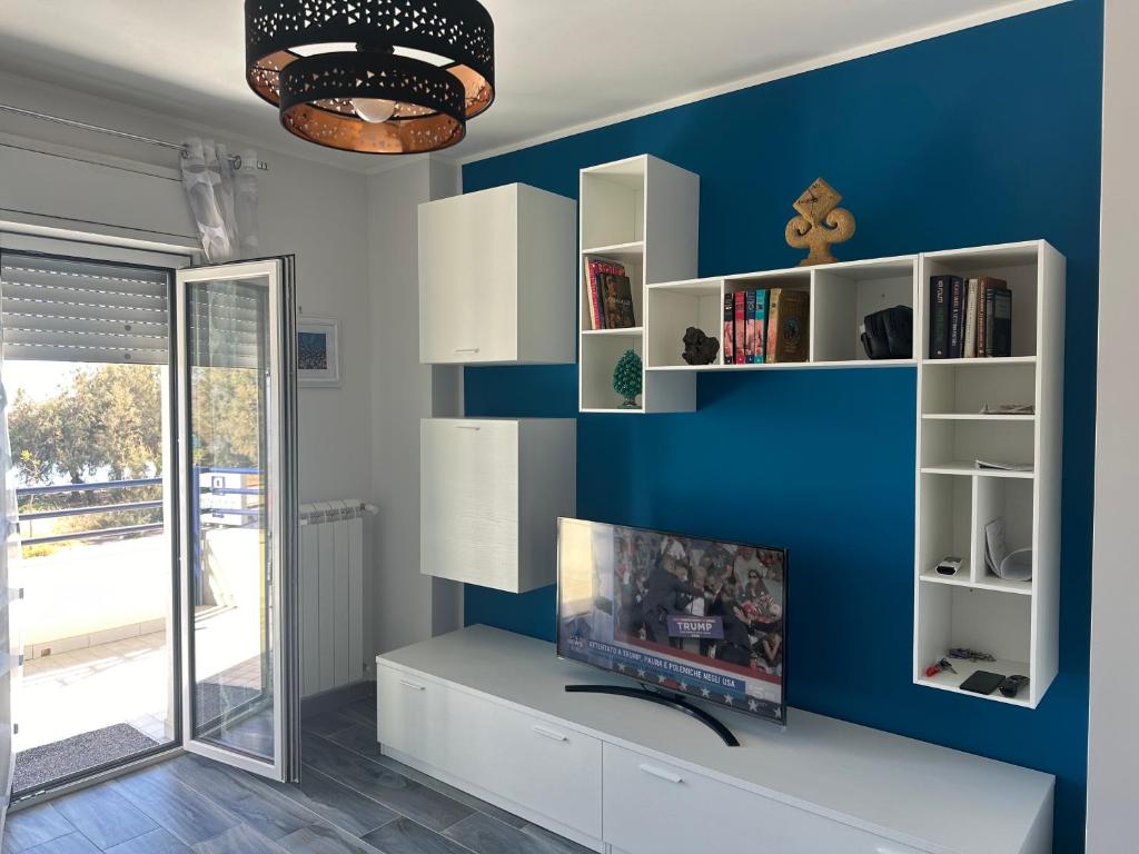 un soggiorno con parete blu e TV di Casa vacanze Rosalinda House di fronte al mare di Palermo a Palermo