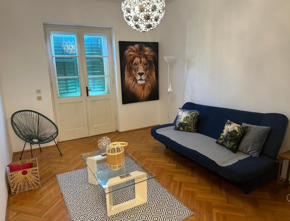 a living room with a blue couch and a lion painting at Split City Center Apartment in Split