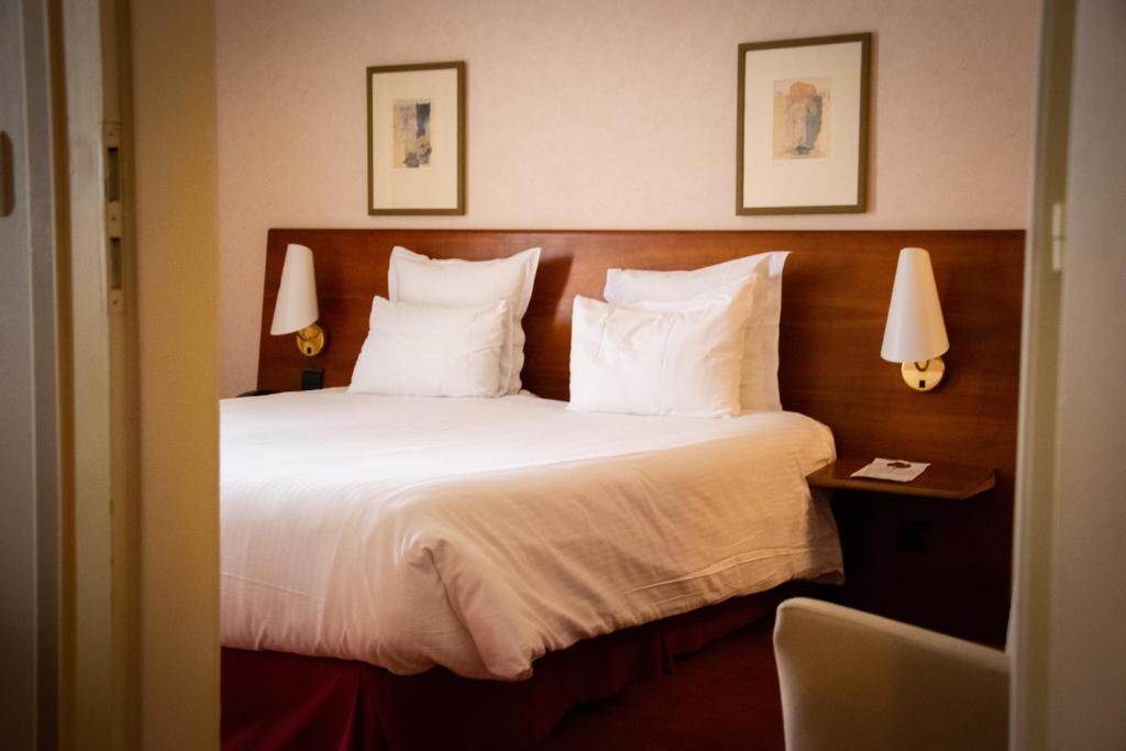 Cette chambre comprend un lit avec des draps et des oreillers blancs. dans l'établissement Le Jean-Sébastien Bach, à Strasbourg