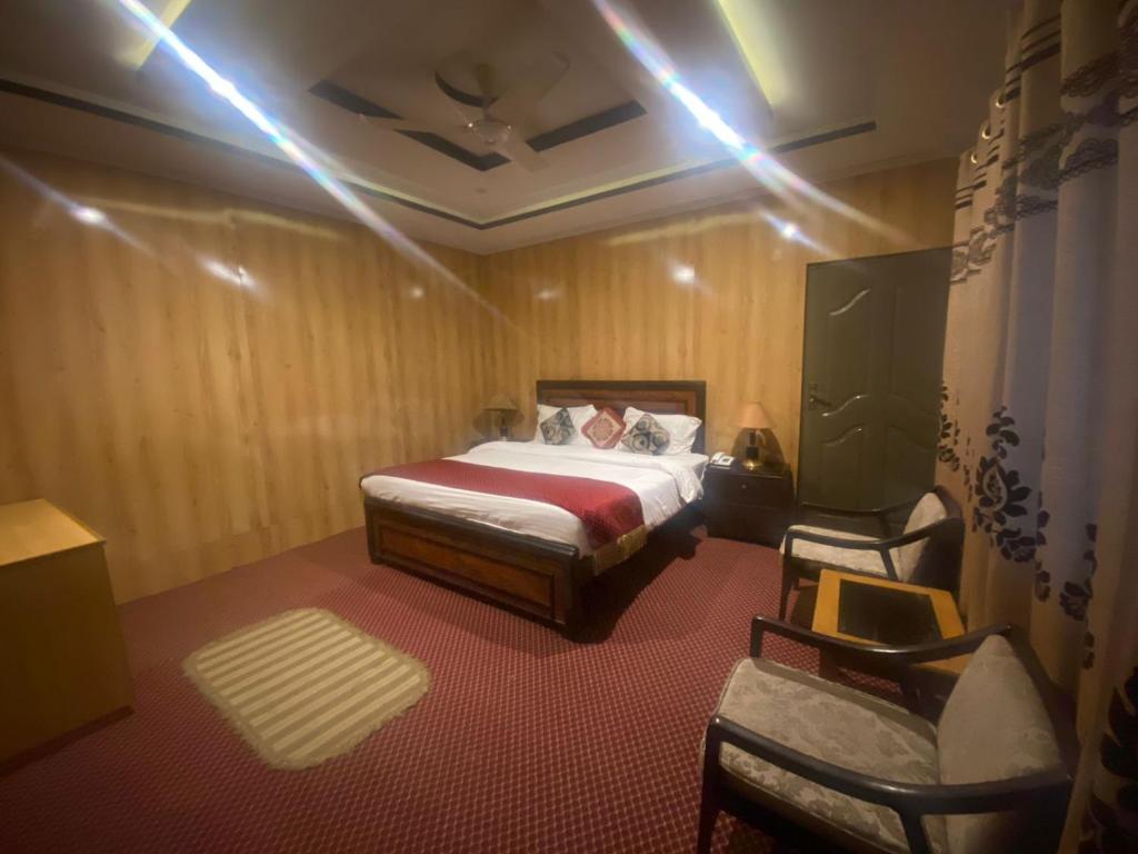 a bedroom with a bed and two chairs in it at Hotel Blangsa Indus View in Skardu