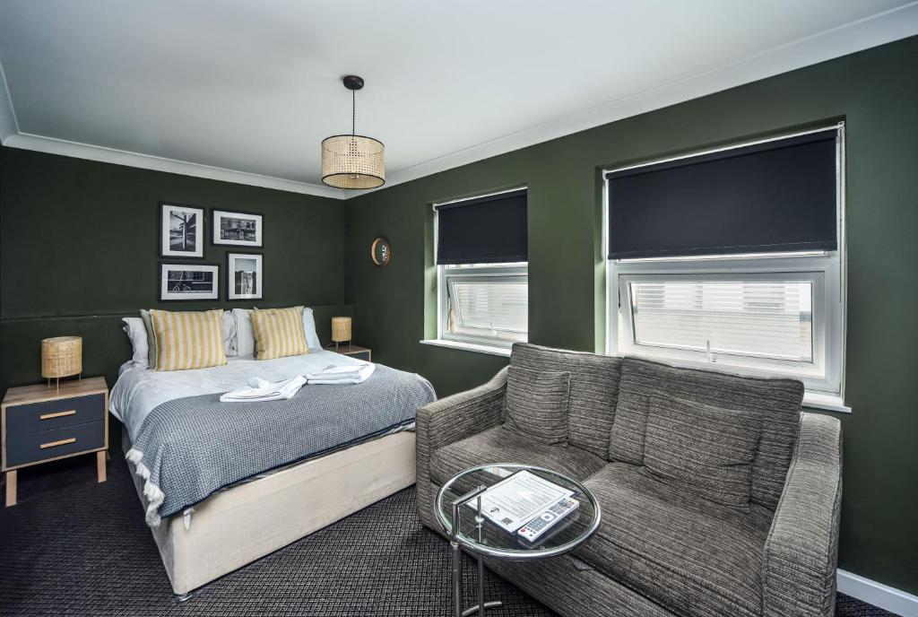 a bedroom with green walls and a bed and a couch at Old Ship Inn Hackney in London