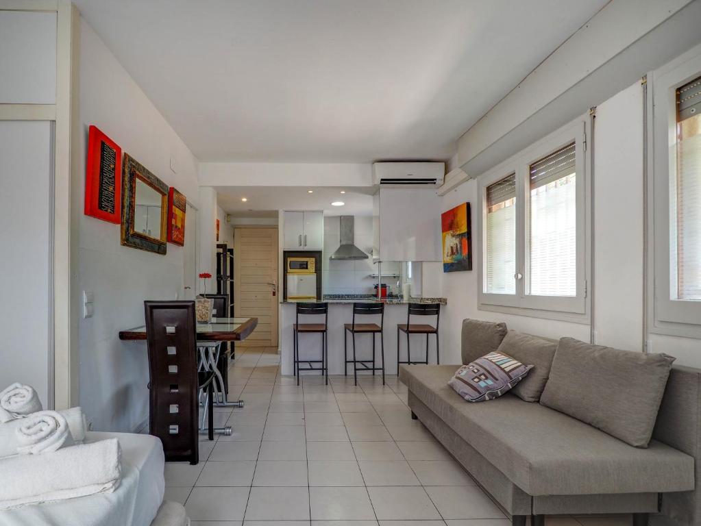 a living room with a couch and a kitchen at Los Globos Beach Studio by Hello Homes Sitges in Sitges