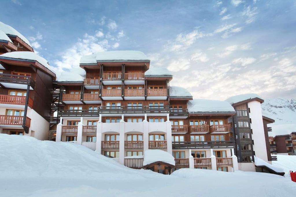 un grand bâtiment avec de la neige devant lui dans l'établissement T2 pour 5 personnes, skis aux pieds - L'ecrin des alpages Belle Plagne, à La Plagne Tarentaise