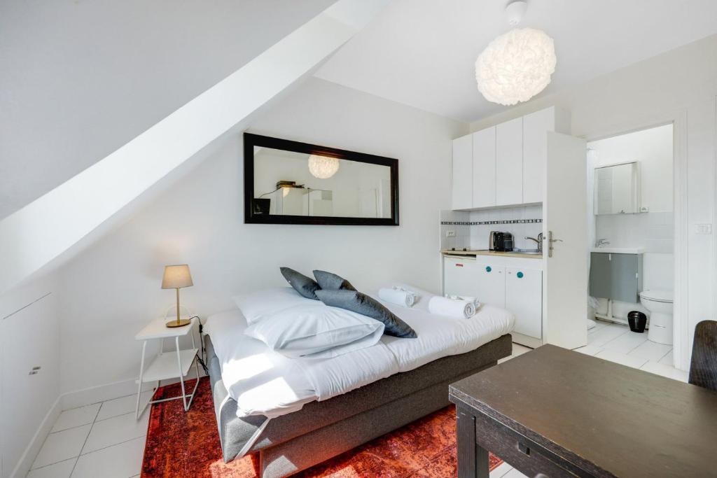 une chambre blanche avec un lit et une table dans l'établissement Paris Marais Rosiers, à Paris