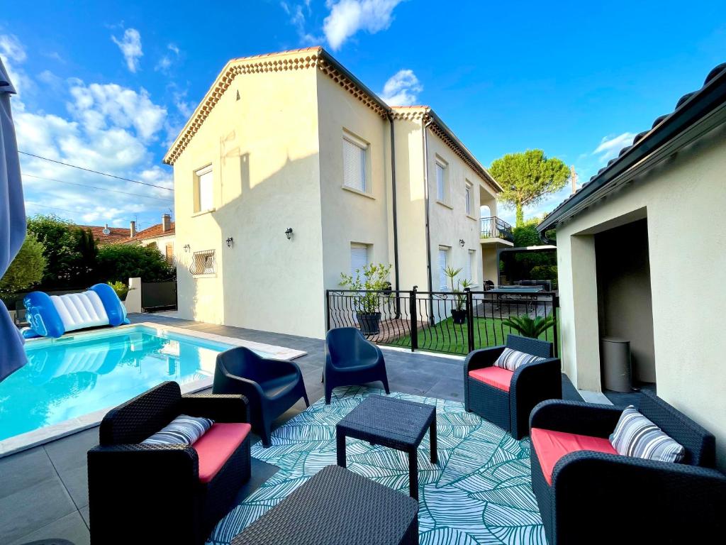 - une terrasse avec des canapés et des chaises à côté de la piscine dans l'établissement Grande maison de vacances, à Alès