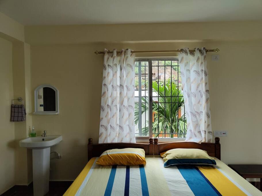 a bedroom with a bed with a window and a sink at Tales of Guwahati 1BHK - ii -AC 200 extra in Guwahati