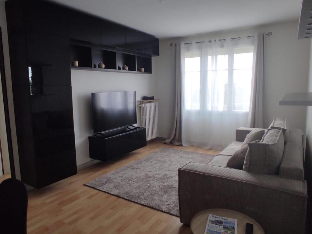 un salon avec un canapé et une télévision à écran plat dans l'établissement Cosy 2 Pièces proche Paris, à Les Pavillons-sous-Bois