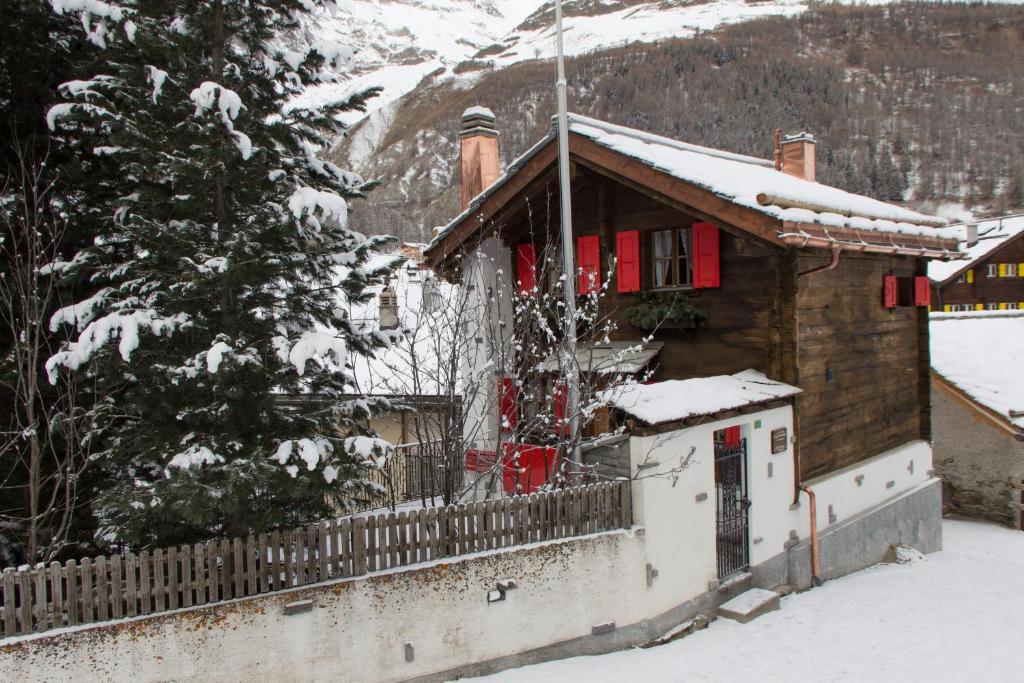 サースフェーにあるChalet Le Caméeの雪の中の赤い扉のある家