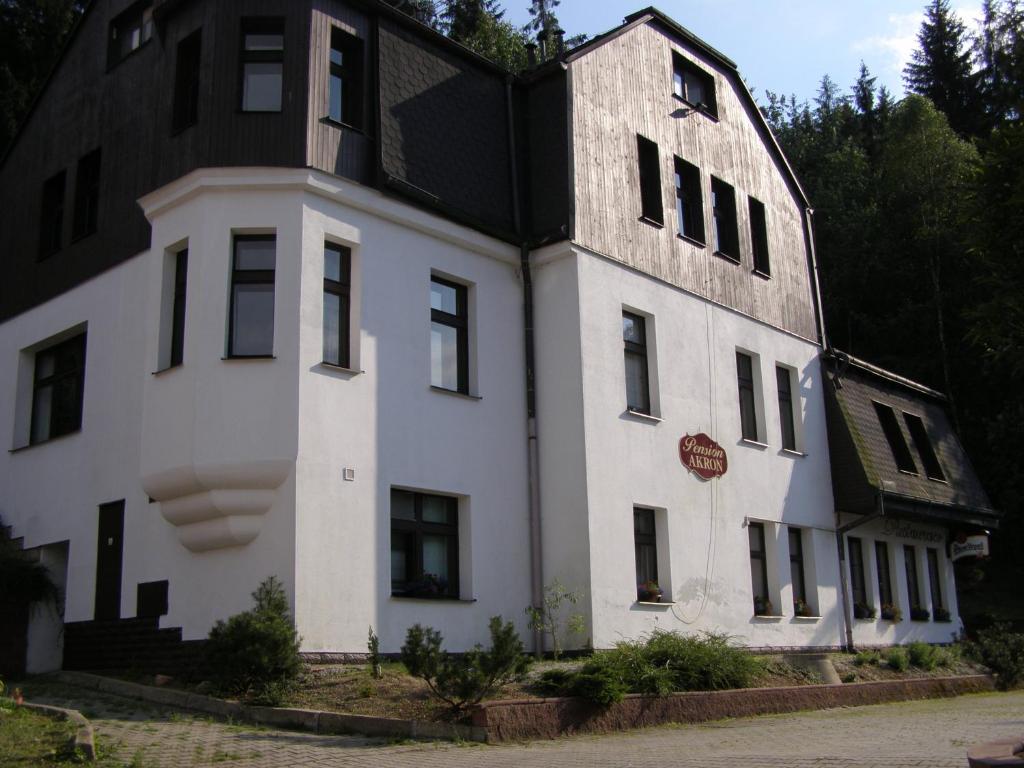 un grand bâtiment blanc avec un toit noir dans l'établissement Penzion Akron, à Tanvald