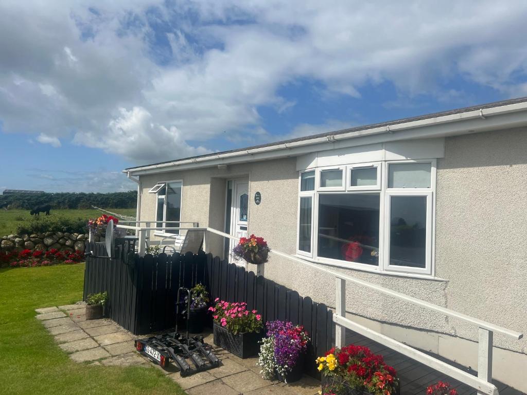 a house with a fence and flowers in the yard at Moneydarragh Cottage with uninterrupted mountain and sea views- Hot tub available for hire in Annalong