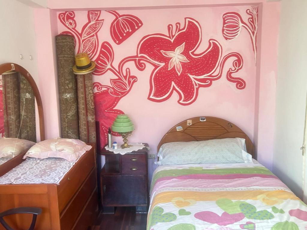 een slaapkamer met een bed en een bloem op de muur bij Casa Manzanapata in Cuzco