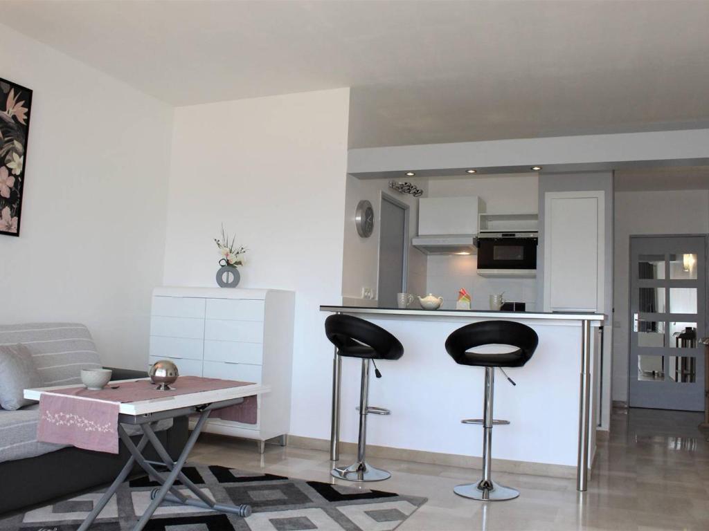 - un salon avec une cuisine et deux tabourets dans l'établissement Villeneuve-Loubet : Appartement climatisé, 2 pièces, 4 couchages, parking en option - FR-1-252A-31, à Villeneuve-Loubet