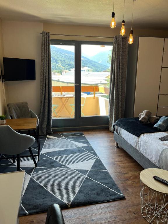 un salon avec un lit et une grande fenêtre dans l'établissement Studio aux pieds des montagnes, à Bourg-Saint-Maurice
