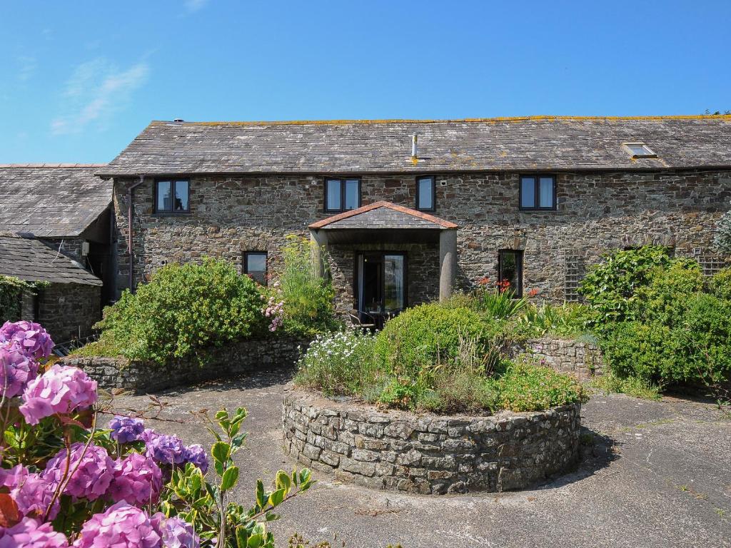 an old stone house with flowers in front of it at West Lee in Bude