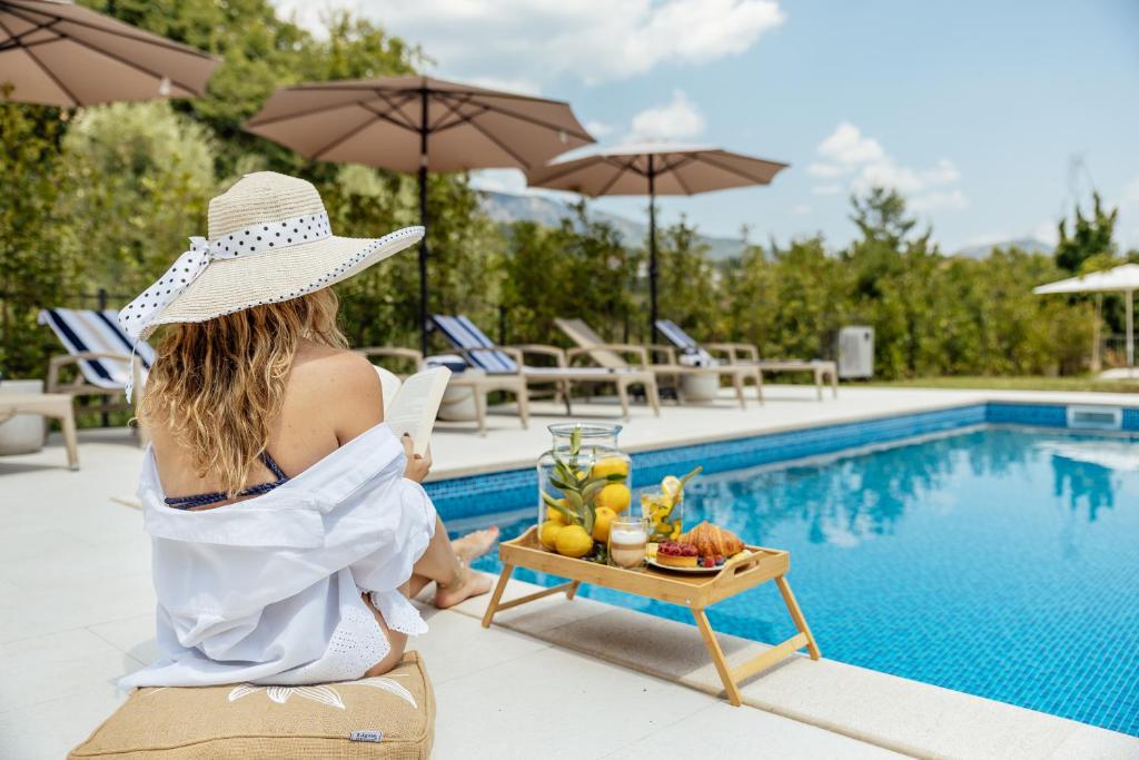 a woman sitting on a chair next to a pool at Albizia in Herceg-Novi