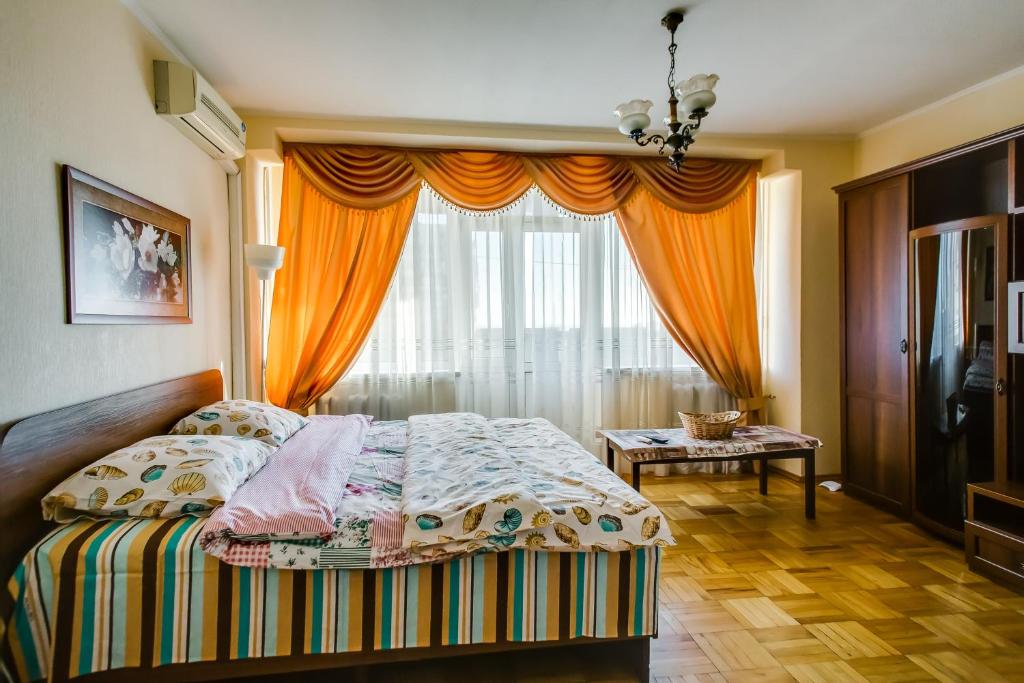 ロストフ・ナ・ドヌにあるApartment on Voroshilovskiyのベッドルーム1室(ベッド1台付)、窓(オレンジ色のカーテン付)