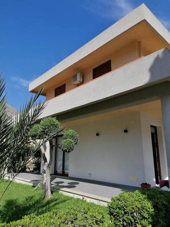 a white house with a palm tree in front of it at Appartamento villa Francesca in Castelluzzo