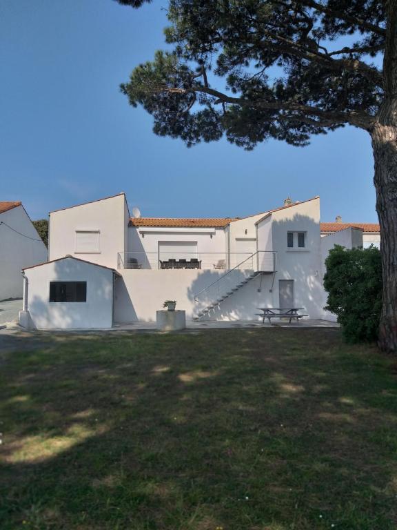 une maison blanche avec un arbre et un banc dans l'établissement Plaisance, à Saint-Georges-dʼOléron