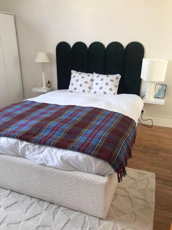 - une chambre avec un grand lit et une couverture dans l'établissement Charmant appartement Batignolles, à Paris