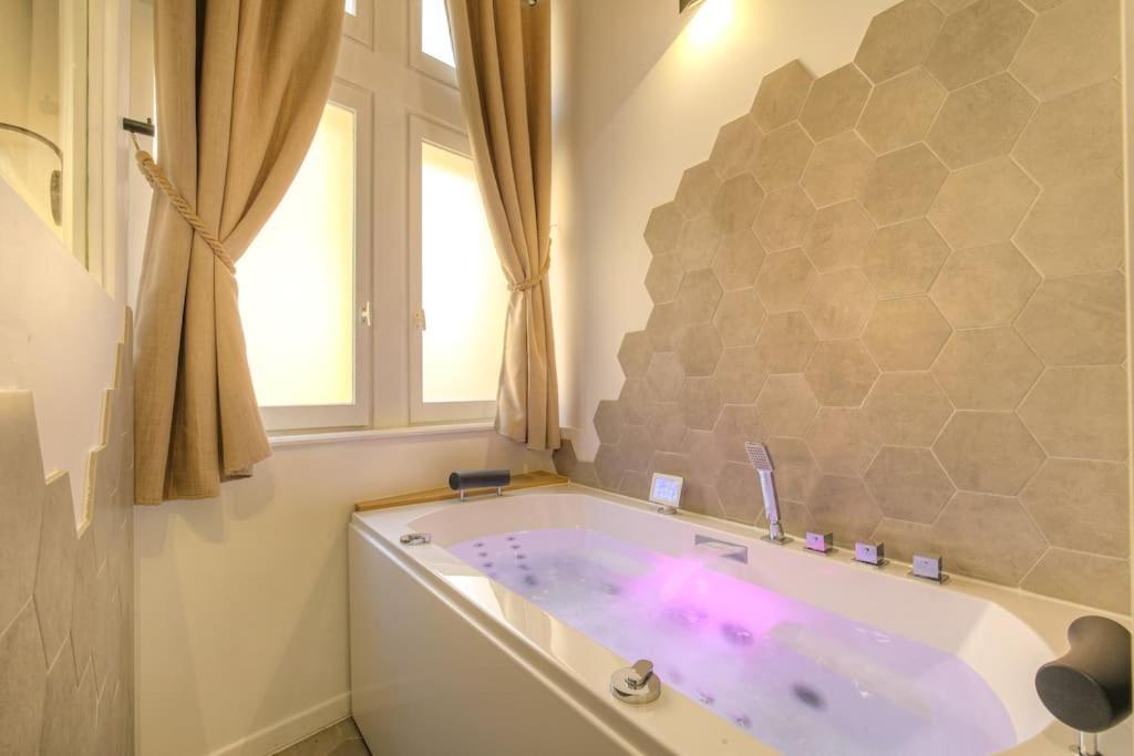 La salle de bains est pourvue d'une baignoire avec un éclairage violet. dans l'établissement Studio de charme avec balnéo, coeur de Presqu'île, à Lyon