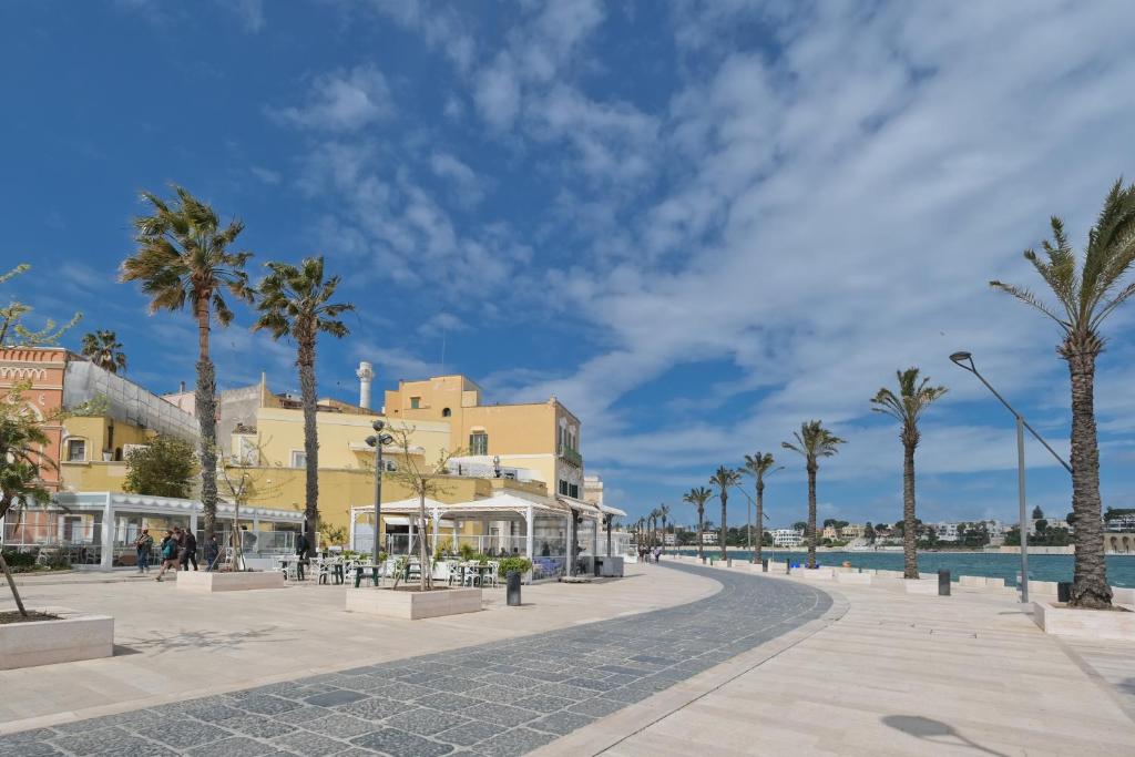 a street in a resort with palm trees and a pool at Hary Home Exclusive Rooms in Brindisi