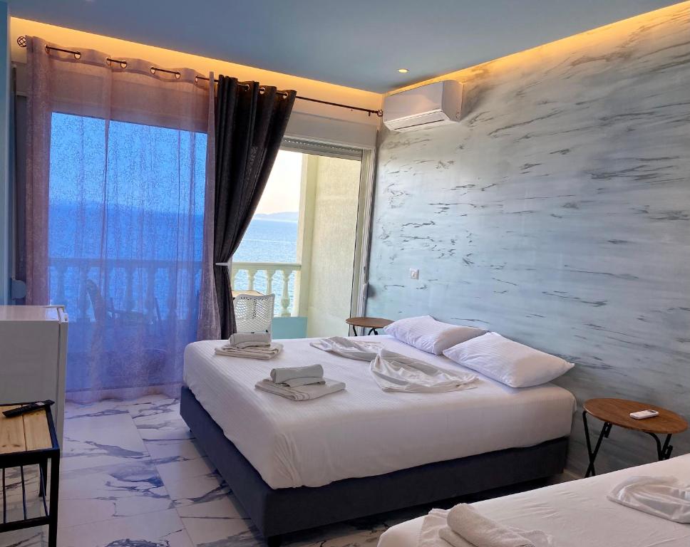 a hotel room with two beds and a large window at Kalemi's Beachside Hotel in Sarandë