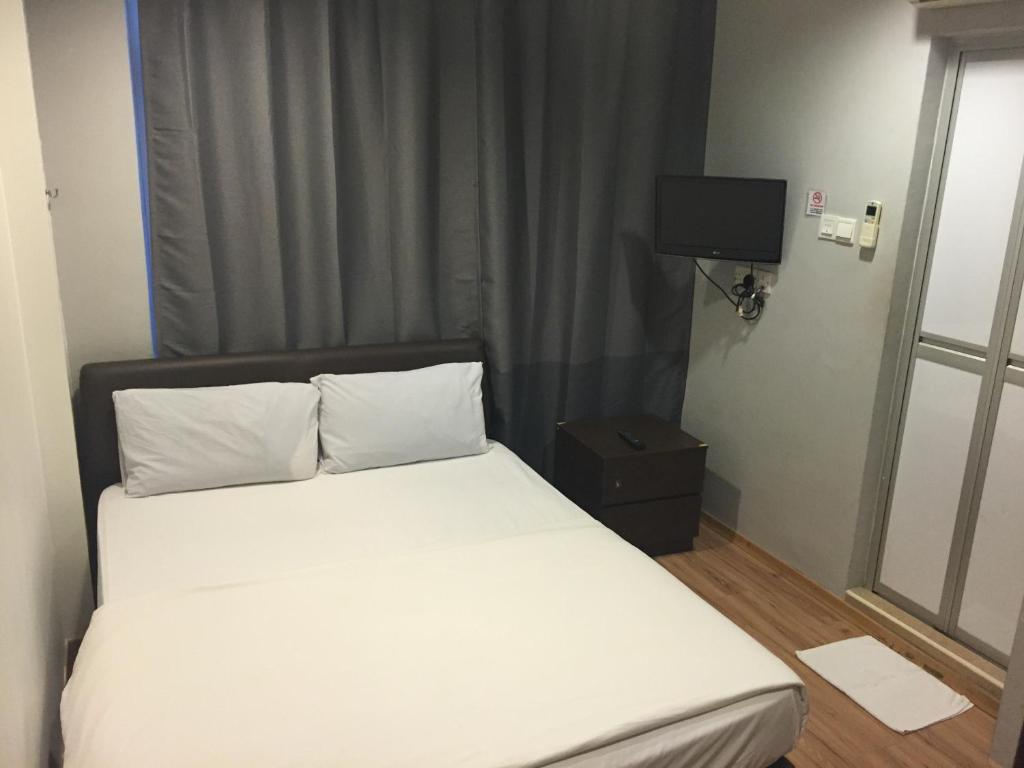 1 cama con sábanas blancas y TV en una habitación en Hotel Conforto en Singapur