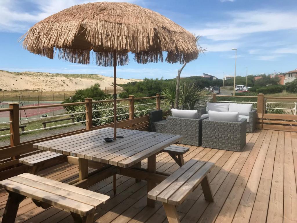 une terrasse en bois avec une table de pique-nique et un parasol dans l'établissement Villa de la dune, à Seignosse