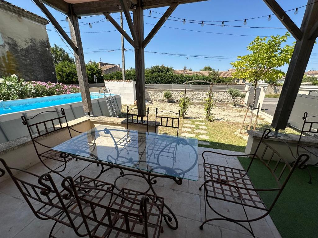 ein Glastisch und Stühle auf einer Terrasse in der Unterkunft Maison Isle sur la sorgue in LʼIsle-sur-la-Sorgue