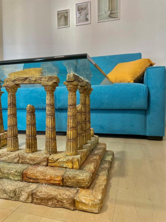 a living room with a blue couch and a glass table at Greco Rooms in Pompei