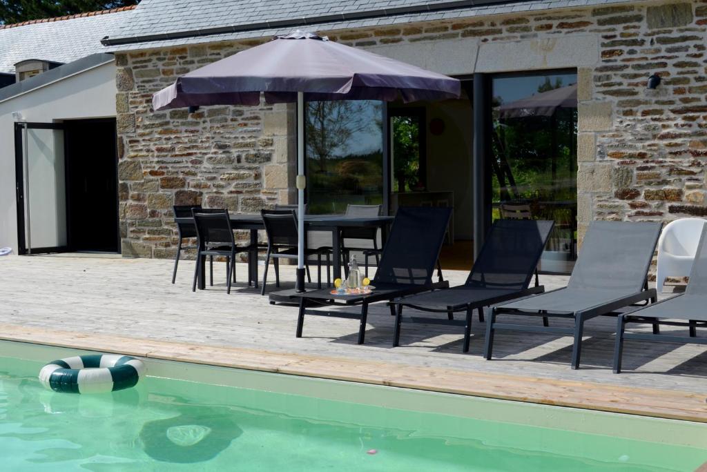 un patio avec des chaises et un parasol à côté d'une piscine dans l'établissement Domaine Sea & Tea, à Plonéour-Lanvern