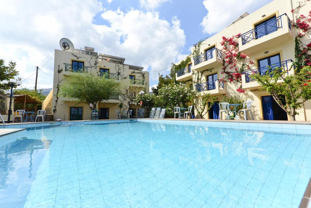 a large swimming pool in front of two buildings at Milos Studios in Malia