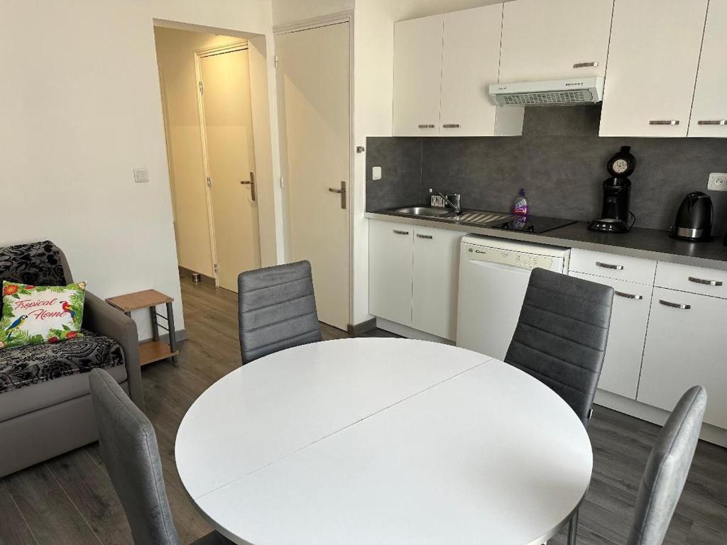 une cuisine blanche avec une table et des chaises blanches dans l'établissement Un petit coin de paradis, à Fort-Mahon-Plage