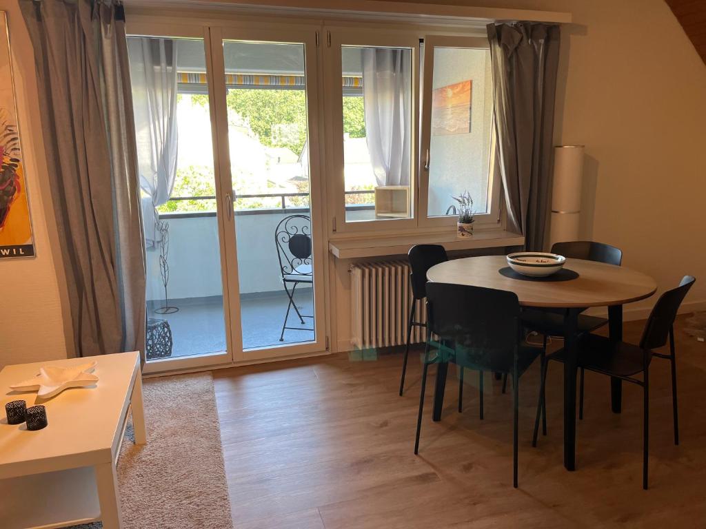 a dining room with a table and chairs and a balcony at Studio Wettingen möbliert, 25min bis Zürich in Wettingen