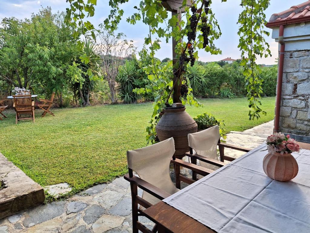 a table with chairs and a vase on a patio at Garden House KRISTI in Possidi