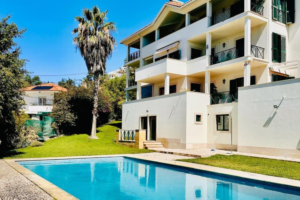 a house with a swimming pool in front of a building at Casa do Mar Cascais in Alcabideche