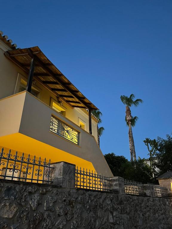 a yellow house with a palm tree in the background at Vivi's Apartments Loft in Spetses
