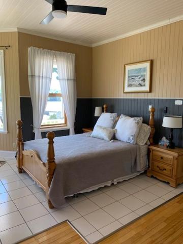 a bedroom with a large bed and a window at Le Manoir du Vieux Presbytère in Port-Daniel