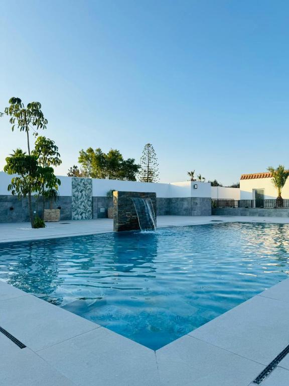 a swimming pool with a fountain in front of a building at Entre Olivos in Níjar