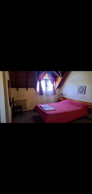 a bedroom with a red bed and a window at Alojamiento Turístico Barrio Belgrano in San Carlos de Bariloche
