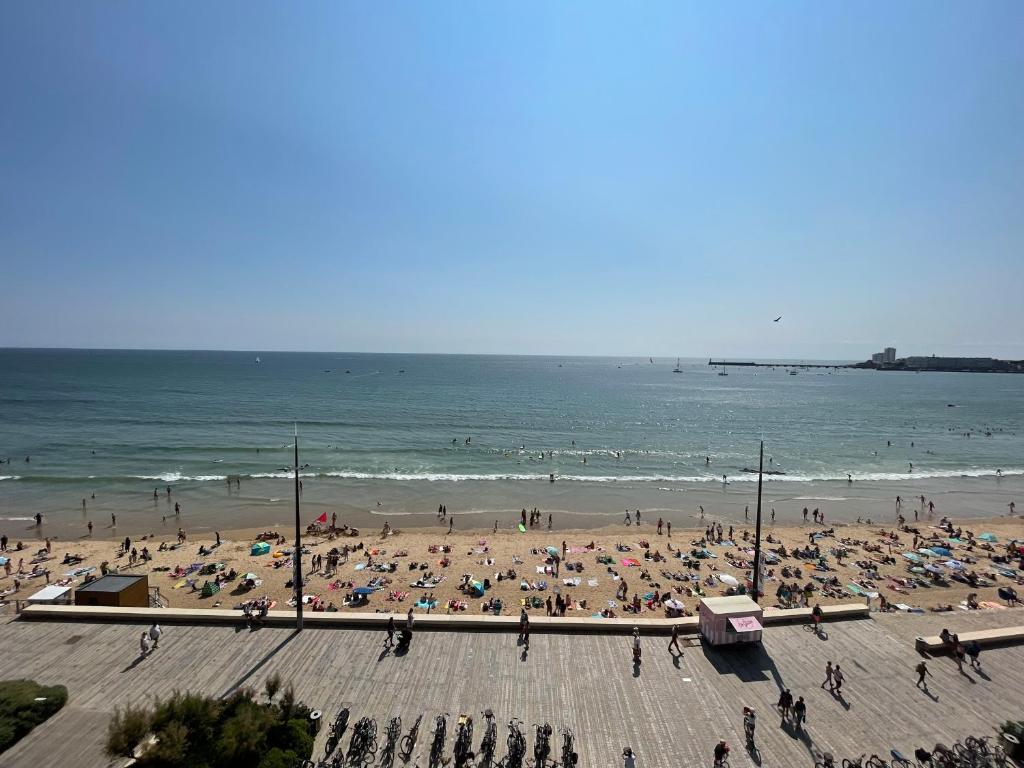 un groupe de personnes sur une plage avec des parasols dans l'établissement Appartement T3 au 6e étage avec balcon et vue mer - FR-1-197-200, à Les Sables-dʼOlonne