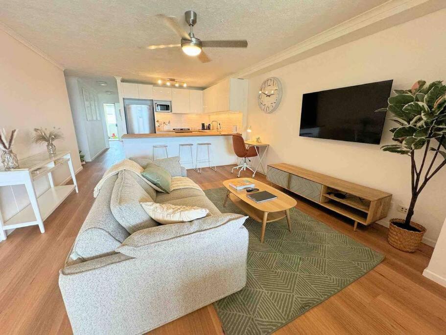 a living room with a couch and a flat screen tv at Spacious Apt with pool & parking in Brisbane