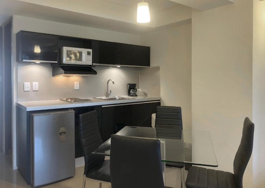A compact suite kitchenette sits beside a glass dining table with four black chairs.
